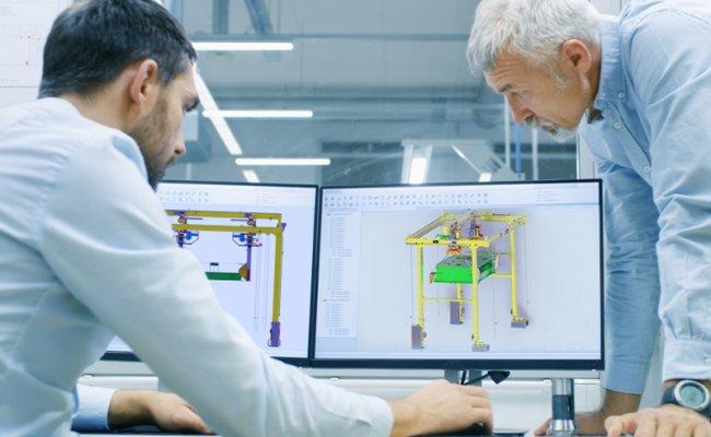 Two people viewing industrial equipment drawings on computer screens